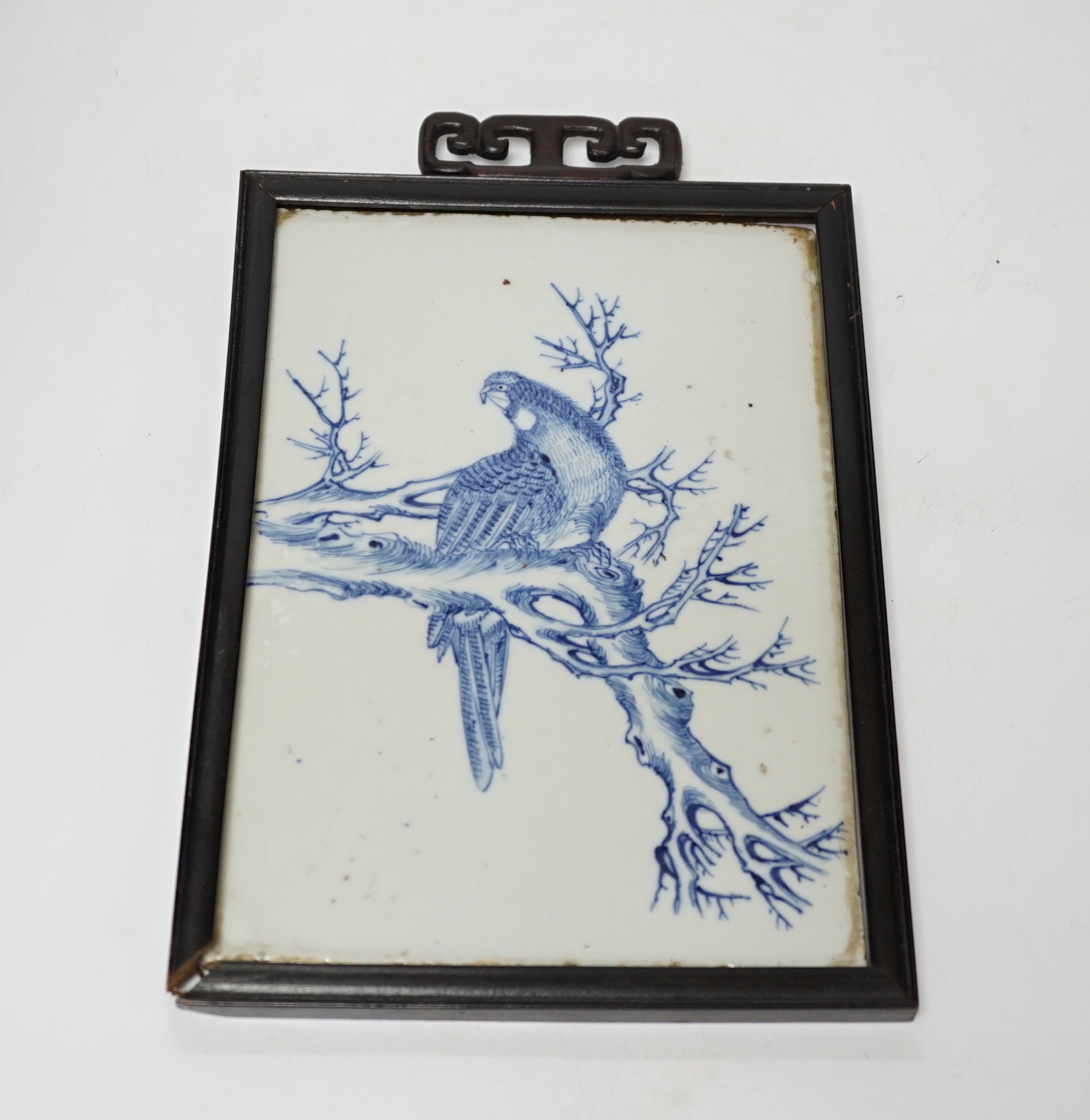 A late 19th century Chinese blue and white plaque of a bird, ebonised frame, 19cm wide x 30cm high including frame